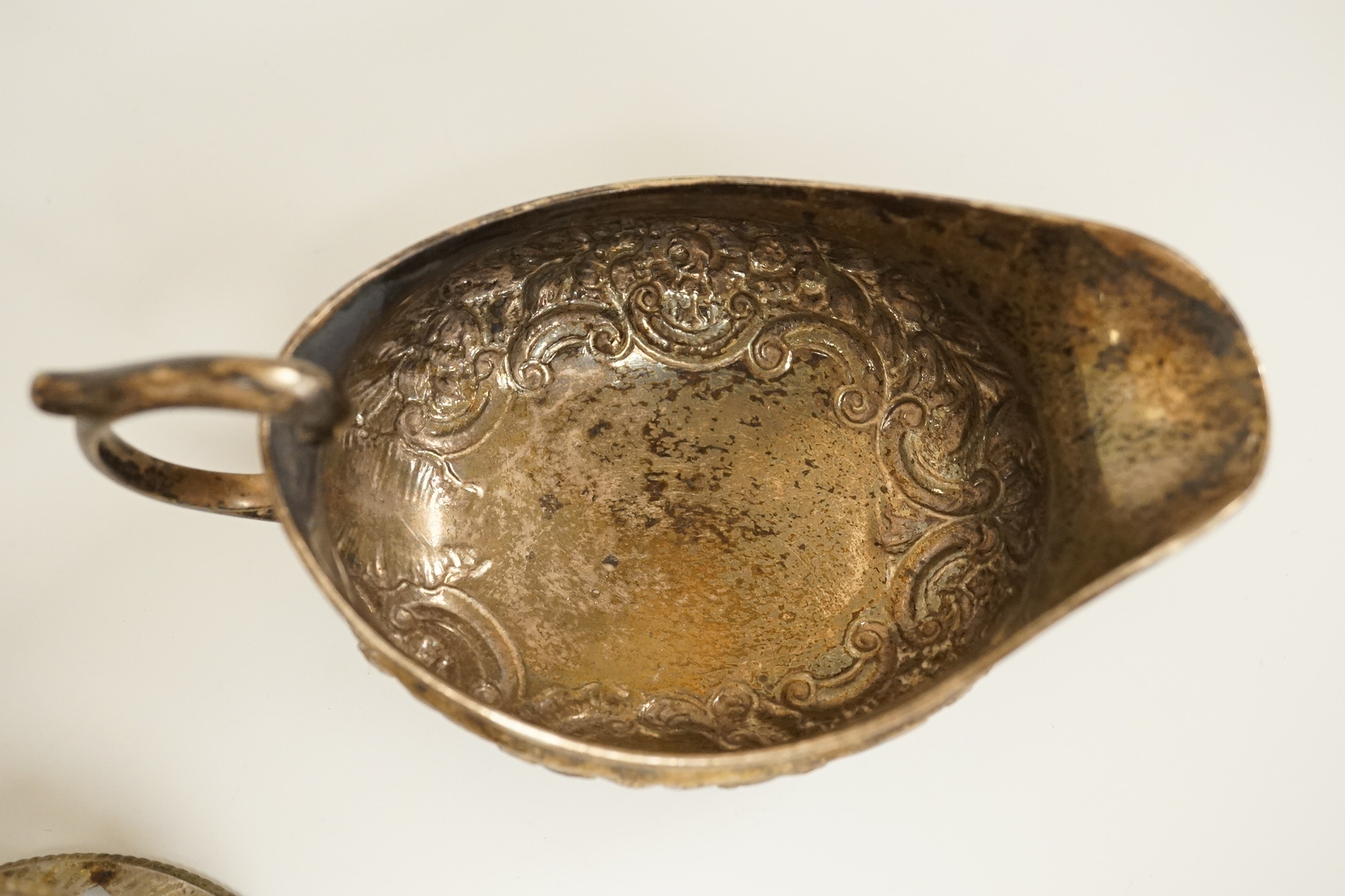A late George III Irish embossed silver sauce boat, with flying scroll handle, maker. ?S, Dublin, 1817, length 14cm, together with a small Edwardian silver dish ring, I S Greenberg & Co, Birmingham, 1901, 7.2oz.